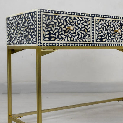Bone inlay console table in navy blue with white vine leaf pattern across three drawers, brass hardware, and gold metal base frame