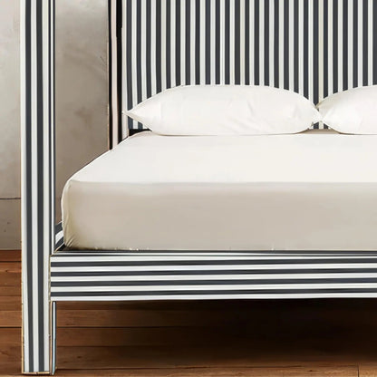 Close-up of bone inlay canopy bed showing striped footboard rail, post inlay detail, and vertical headboard pattern