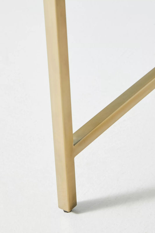 Close detail of the polished brass gold metal base frame and cross bar leg joint of a handmade bone inlay nightstand, showing clean square profile and brushed finish quality.