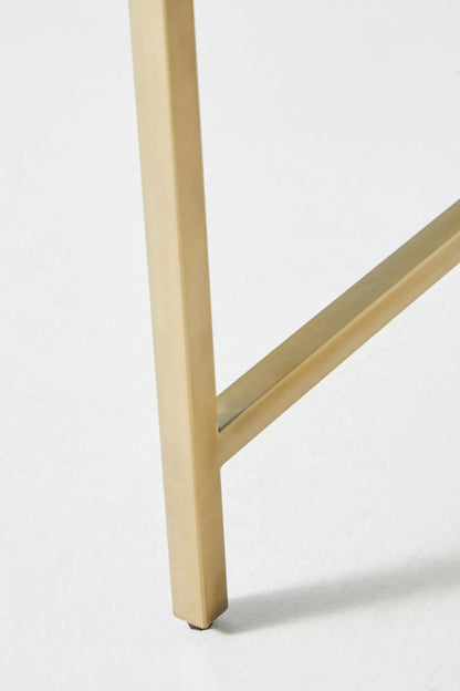 Close detail of the polished brass gold metal base frame and cross bar leg joint of a handmade bone inlay nightstand, showing clean square profile and brushed finish quality.