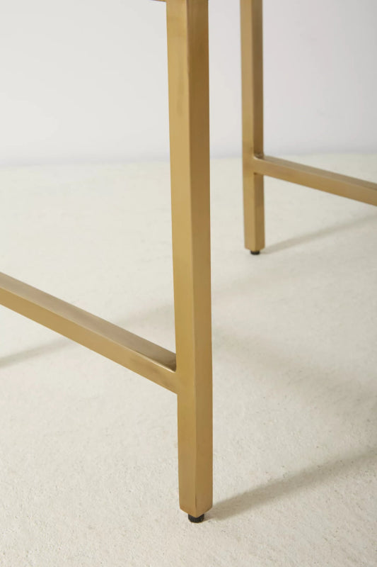 Close detail of brushed brass metal leg and base of handmade bone inlay nightstand, showing clean welded joints and rubber floor protectors for stability and durability.