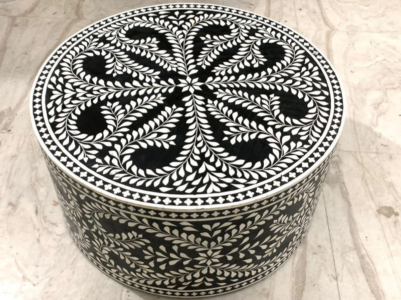 Overhead view of a black and white bone inlay round coffee table featuring an intricate floral medallion with radiating leaf sprays and diamond dot border on the tabletop surface.