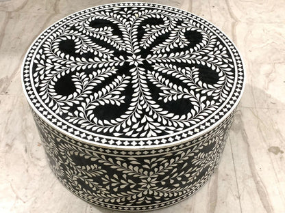 Overhead view of a black and white bone inlay round coffee table featuring an intricate floral medallion with radiating leaf sprays and diamond dot border on the tabletop surface.