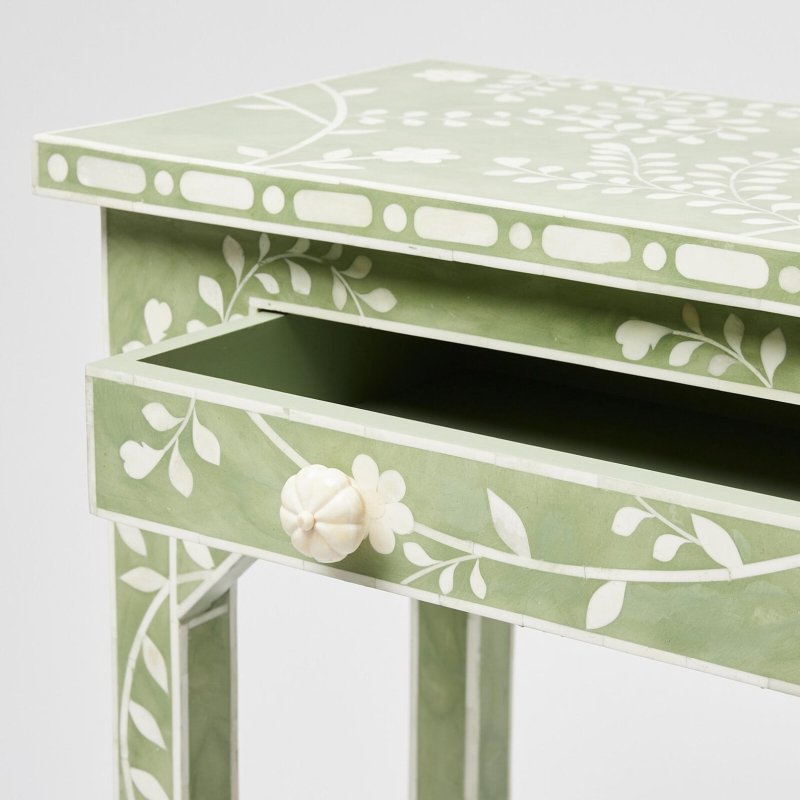 Sage green bone inlay console table with open single drawer revealing interior depth, white floral vine inlay on apron, and carved bone knob against a neutral background