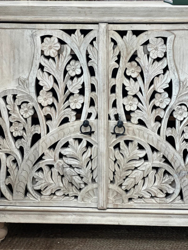 Botanical carved door cabinet in rustic wood, front view of paired doors with floral fretwork and dark ring handles.
