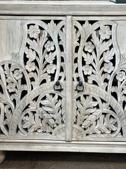 Botanical carved door cabinet in rustic wood, front view of paired doors with floral fretwork and dark ring handles.