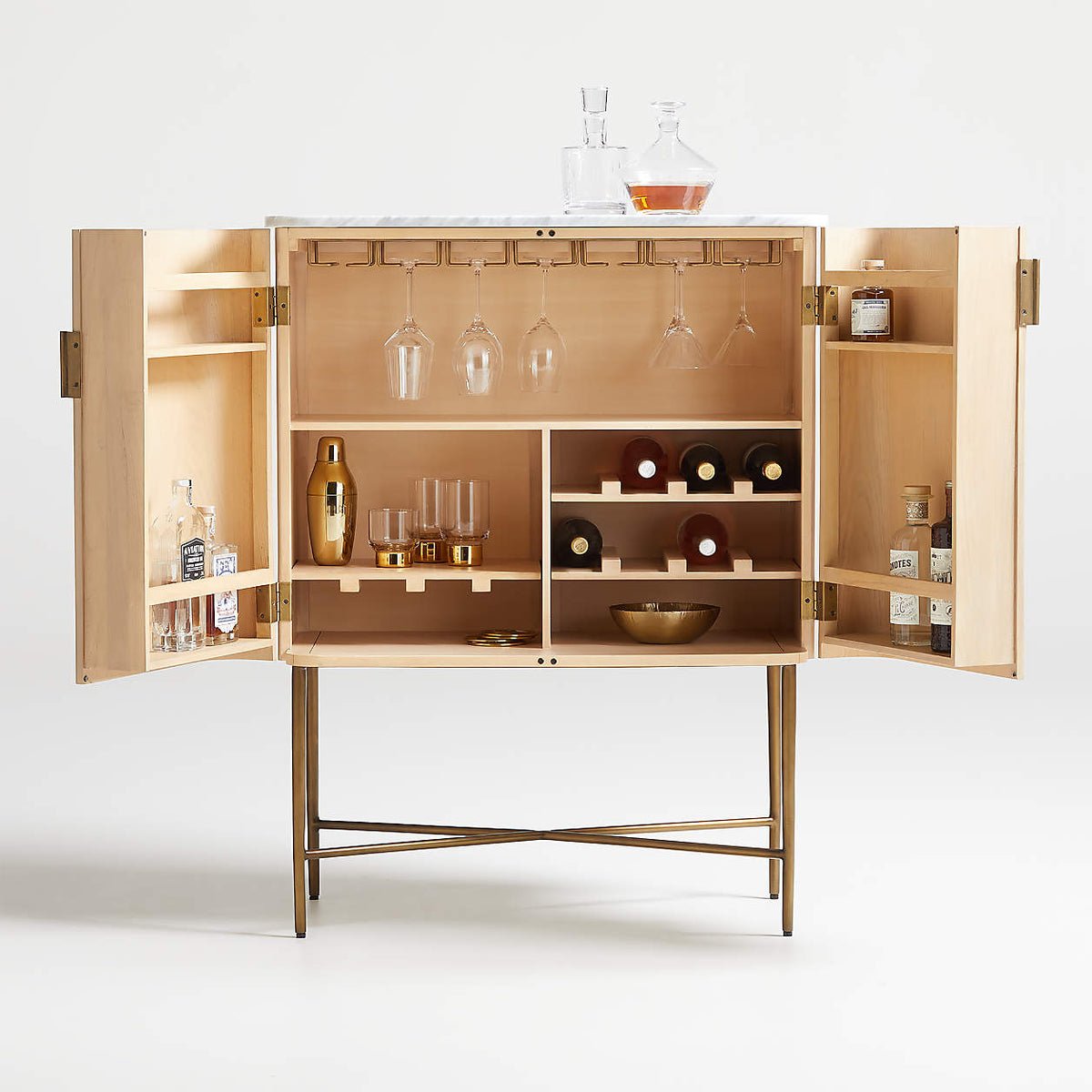 Brass hardware drinks cabinet with both doors open, revealing hanging glassware, wine racks, and bar tools inside.