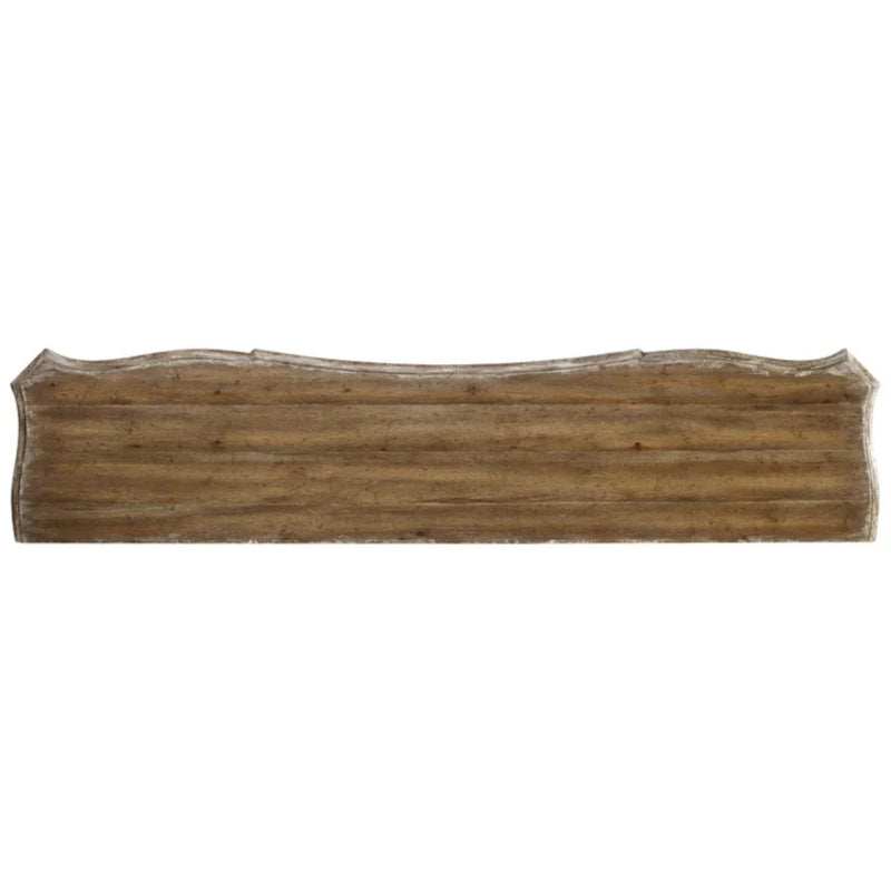 Zoomed-in view of the brown wood top edge on the carved white cabinet, isolated against a pale background
