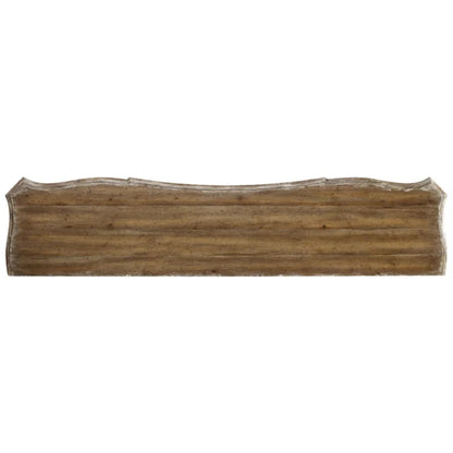 Zoomed-in view of the brown wood top edge on the carved white cabinet, isolated against a pale background