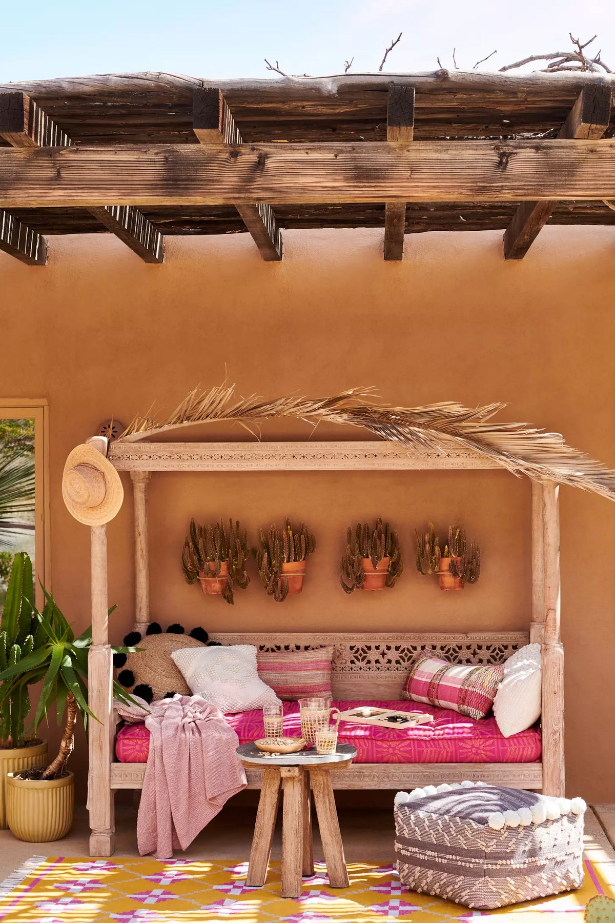 Canopy daybed sofa with carved wood structure, open sides, and comfortable lounge seating.