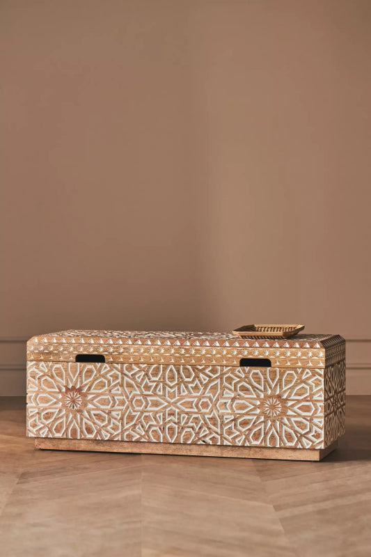 Carved storage trunk with a patterned front and dark hardware, shown straight on with the lid closed.
