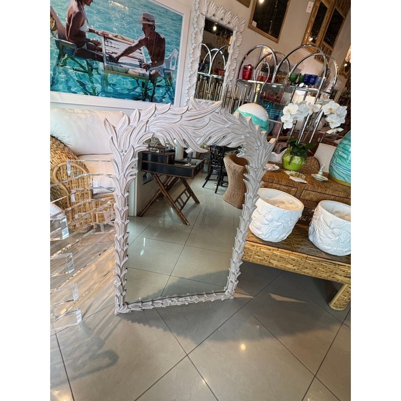 Carved botanical decorative mirror in rustic wood, front view beside a woven bench holding two white planters.