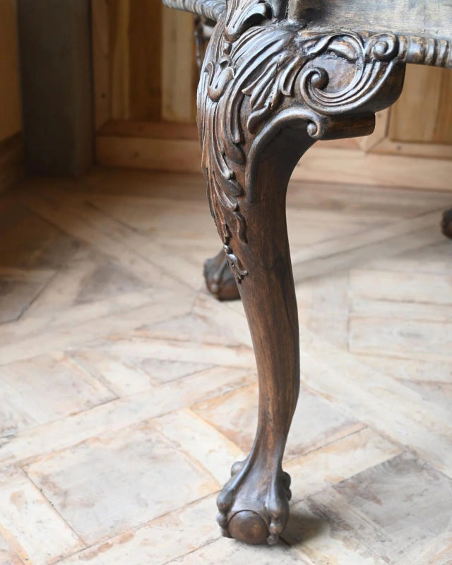 Carved cabriole center table shown close-up at a leg, highlighting its curved shape and rounded foot.