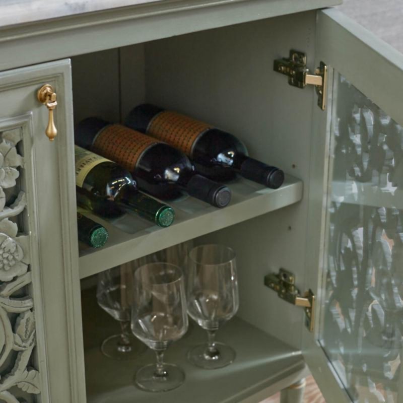 Carved door storage cabinet in rustic solid wood, open door detail showing wine bottles and glasses on interior shelves.