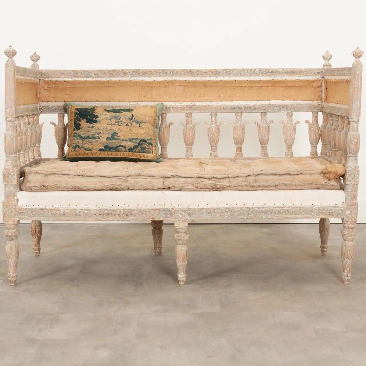 Carved hall bench in pale wood with a cushioned seat, front view showing its open slatted back and turned legs.