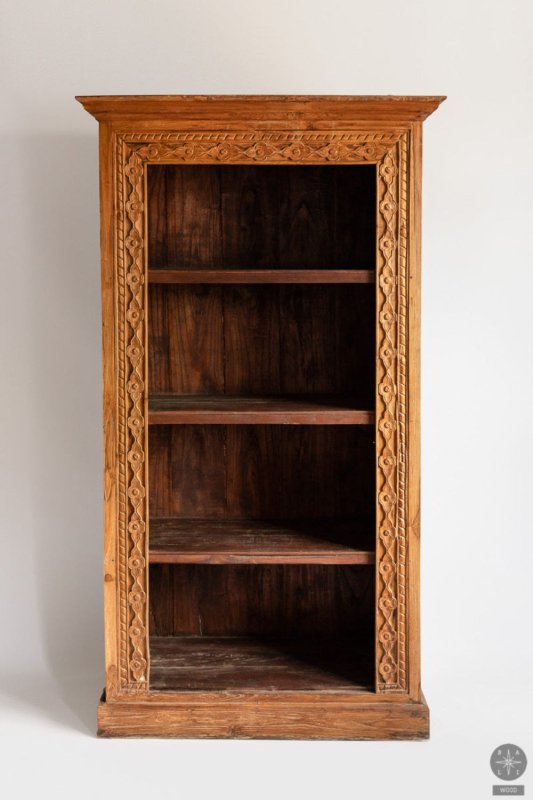 Carved open shelving unit in warm-toned wood, shown at an angle with its recessed shelves and decorated outer frame.