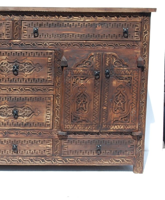 Carved panel wood sideboard in rustic timber, cropped front view of right cupboard doors, dark pulls and drawer borders.