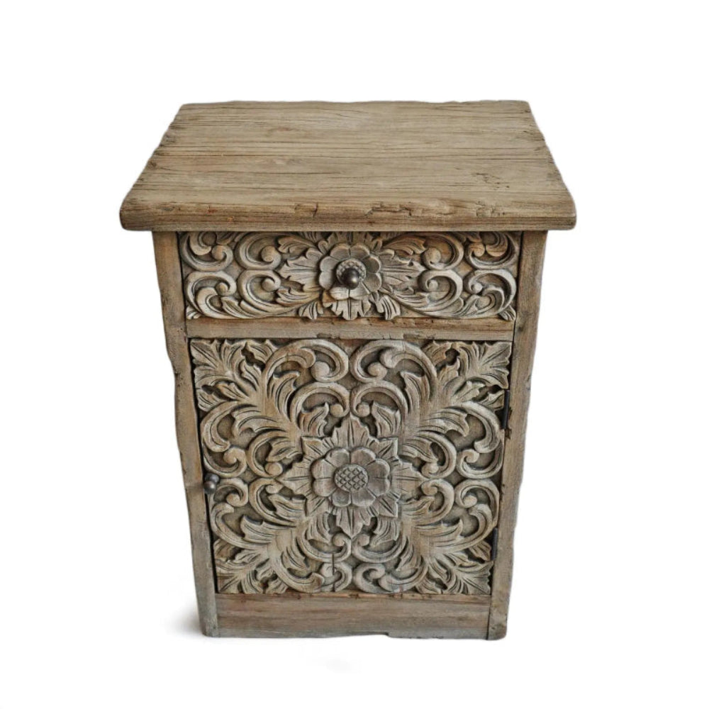 Carved solid wood bedside table in a rustic finish, front view showing a floral drawer and carved cabinet door.