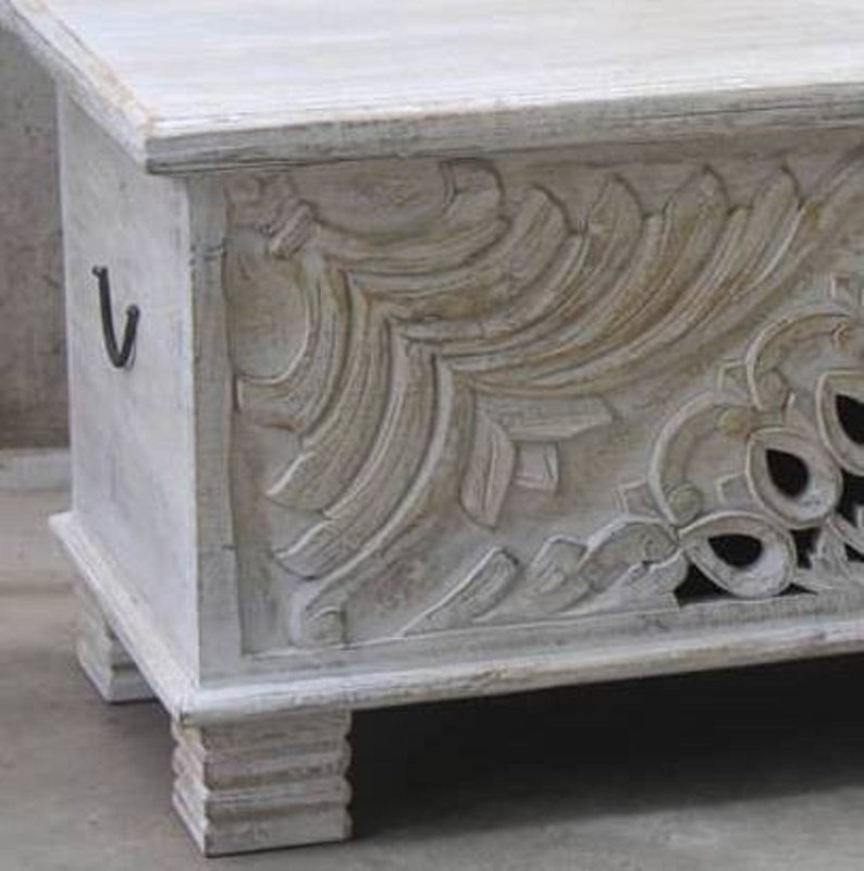 Rustic carved storage trunk in solid wood, corner detail view showing sweeping relief carving and a dark side handle.