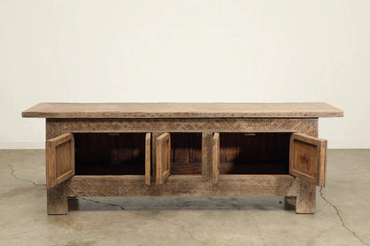 Hand-carved wood buffet with its doors open to show the interior compartments, front view against a pale wall.
