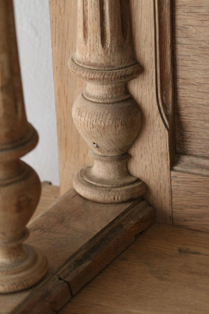 Carved wood china cabinet with a lower corner and shaped foot, close-up beside a pale wall and floor.