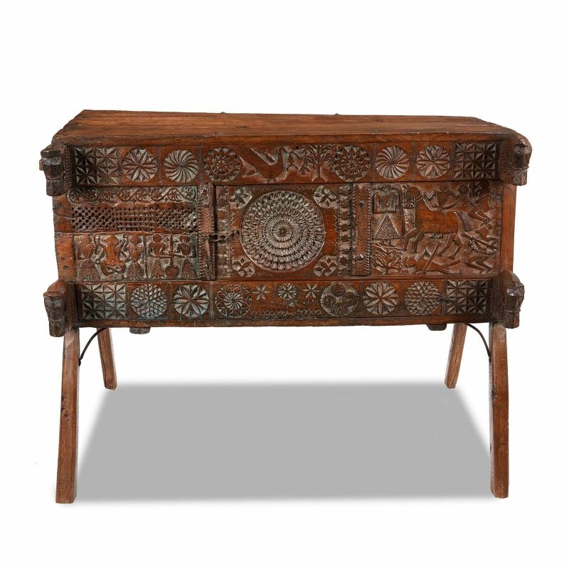 Carved wood dowry chest in natural walnut finish, front view showing a circular center panel and splayed legs.