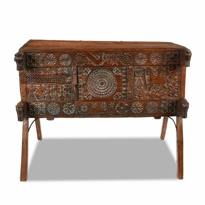 Carved wood dowry chest in natural walnut finish, front view showing a circular center panel and splayed legs.