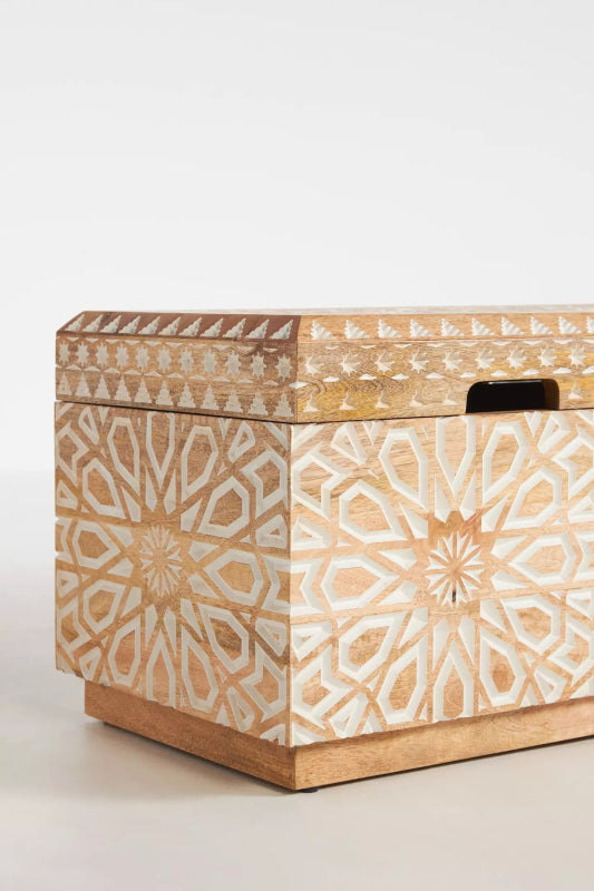 Carved wood storage toy chest shown at an angle, with its closed lid, front corner and one side visible.