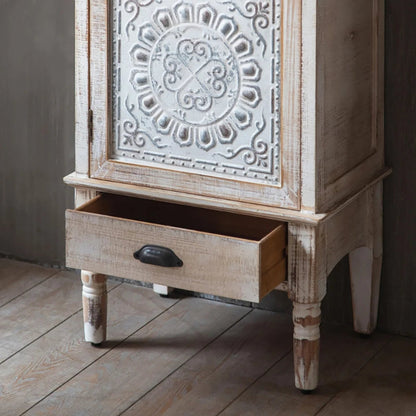 Carved wood tower cabinet in an open drawer view, showing the shallow lower drawer beneath its floral door.