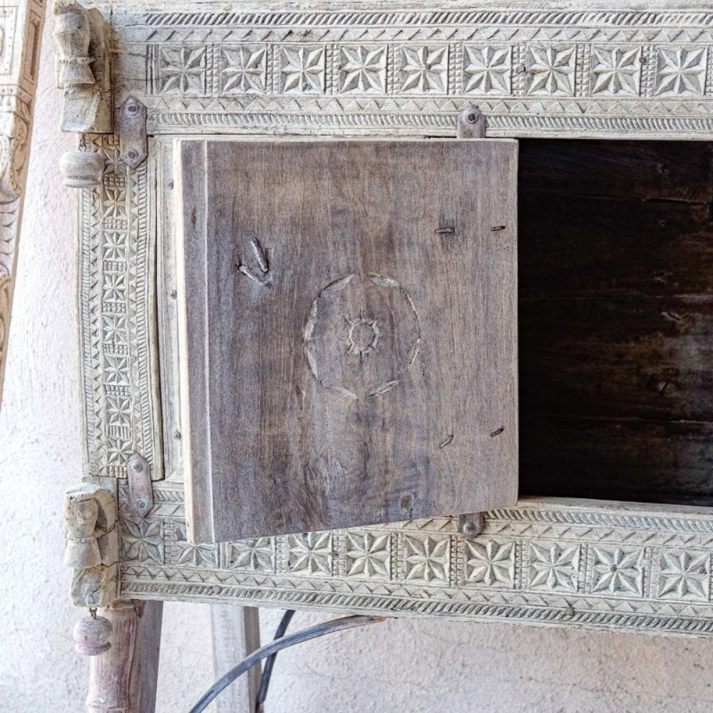 Carved wood trunk chest in a weathered neutral finish, front view detailing the open door and dark interior.