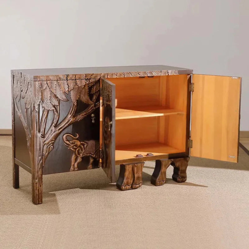 This wooden buffet features an elephant design carved into its doors, framed by decorative jungle foliage.