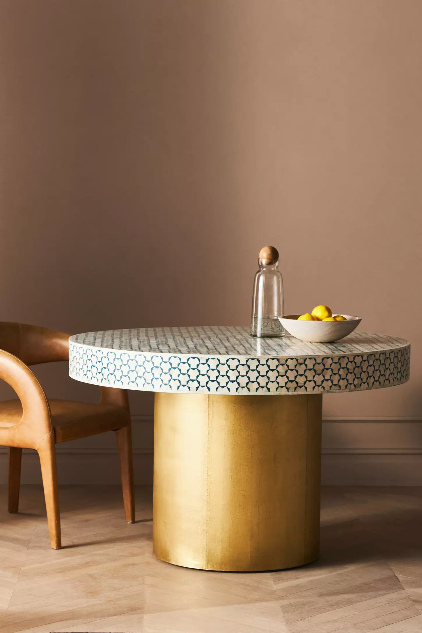 Handcrafted bone inlay round dining table with geometric pattern and gold metal base, styled in a luxury living room