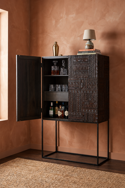 Charcoal wood cabinet in a detail view, with hand-carved geometric patterns across its two-door front.
