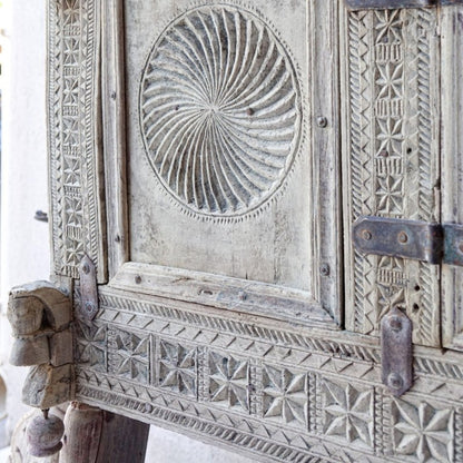 Circular-carved wooden hope chest in a weathered finish, corner detail view showing spiral relief and metal hinges.
