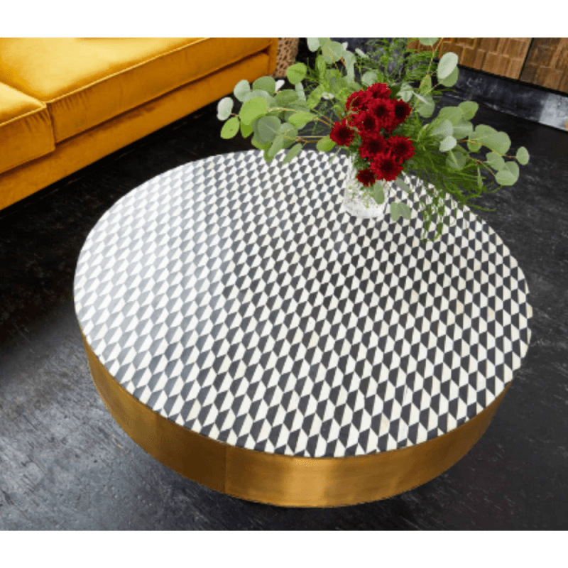 Top view of a round bone inlay coffee table with a black and white checkerboard diamond mosaic pattern, framed by a wide gold metal rim and centered over a black pedestal base, emphasizing the geometric tabletop design.