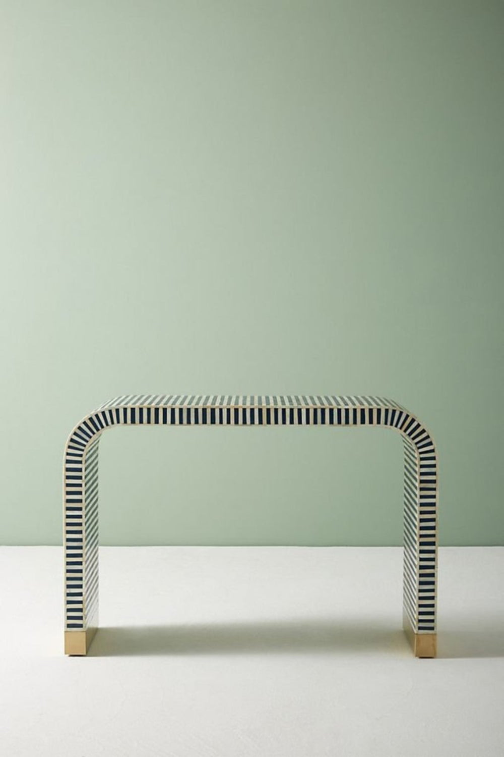 Front angle of the blue bone inlay console table, showing the curved waterfall silhouette, linear stripe pattern across the face and top, and brass-capped feet. The portrait product view keeps the handmade entryway table centered for clear visibility of its blue finish.