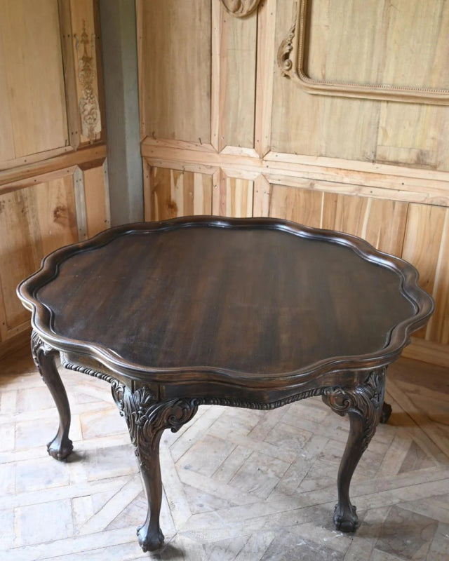Dark round occasional table seen from above, showing the broad tabletop and its gently shaped outer edge.