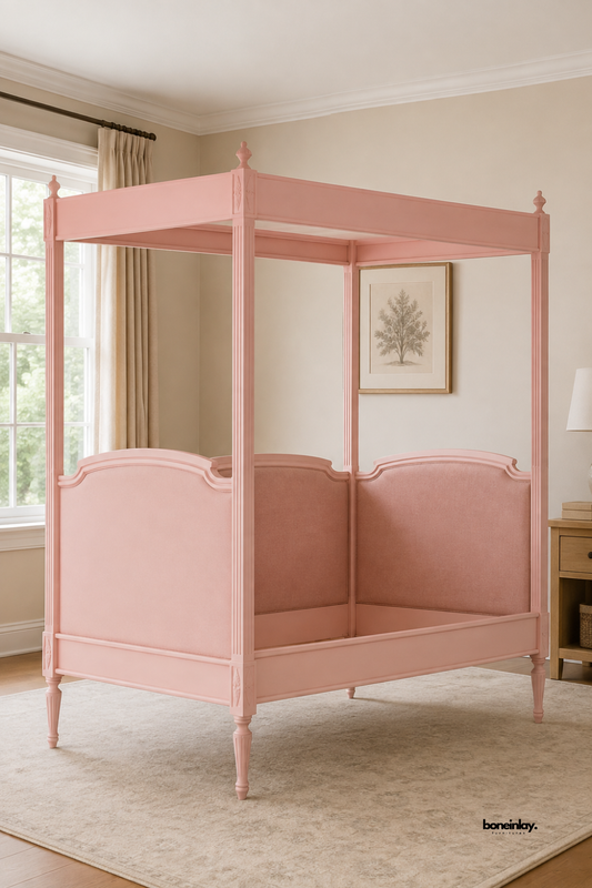 Artisan-crafted pink wooden four-poster canopy day bed styled in a bright British bedroom interior with neutral drapery and warm decor. This luxury statement bed brings a sophisticated pop of color and classic charm to modern UK homes.