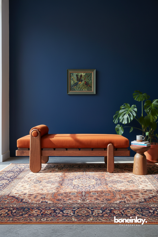Contemporary wooden chaise lounge with burnt orange upholstery styled against a deep navy accent wall.
