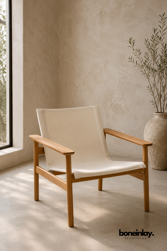 Teak wood lounge chair with a canvas sling seat and backrest.
Angled wood arms and a simple four-leg frame define its shape.
Natural cream fabric offers a relaxed, breathable seating surface.
Placed near a tall vase and window in a warm, minimalist room.