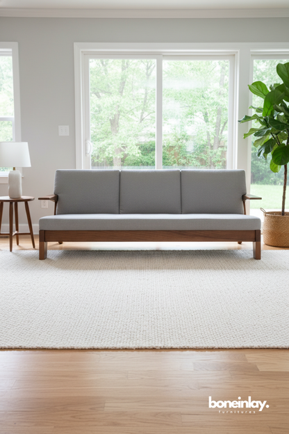 Mid-century wooden sofa bench with grey upholstery in a bright modern living room.