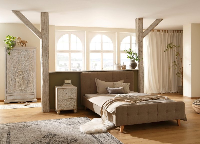 Distressed White Armoire styled in a bedroom, shown at a wide front angle beside a bed and bedside cabinet.