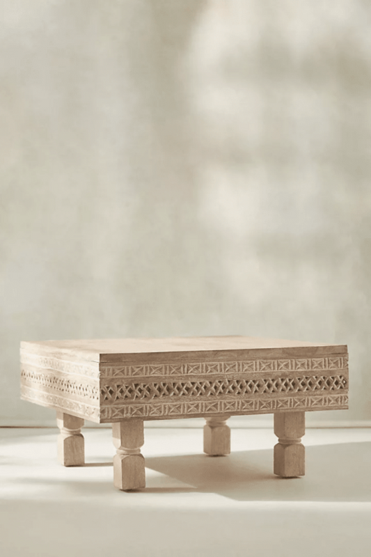 Ezana sand-finish wood coffee table with a square carved frame and geometric lattice band, shown in a front view.