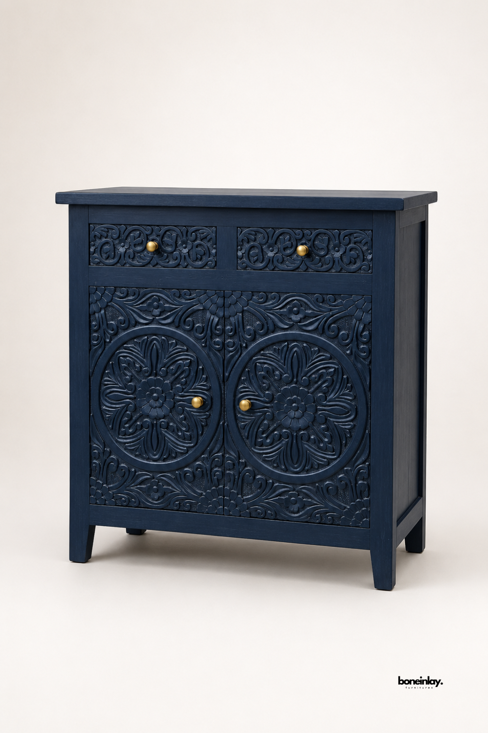 Navy blue hand-carved wooden cabinet with two floral medallion doors and two matching carved drawers. Finished with elegant gold-tone knob hardware for a refined contrast against the deep blue tone. Tapered legs add a classic silhouette suited for dining rooms, entryways, or living spaces. A bold, artisan-crafted storage piece with intricate detailing throughout.