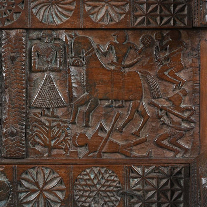 Figural carved hope chest in natural solid wood, front view close-up showing a horse, human figures and floral borders.