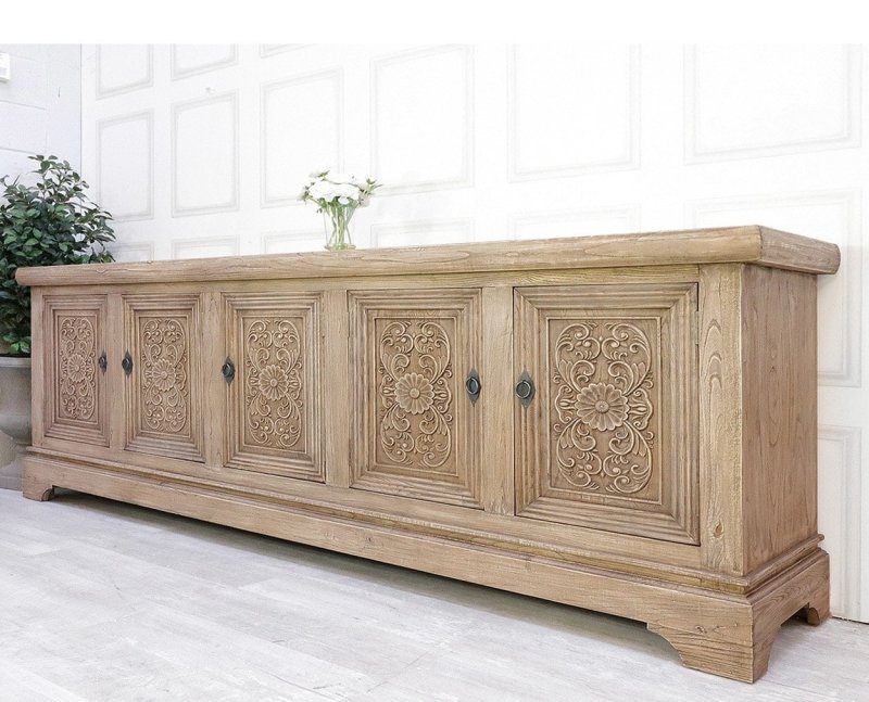 Light wood buffet in a detail view showing circular floral relief carvings repeated across its five door fronts