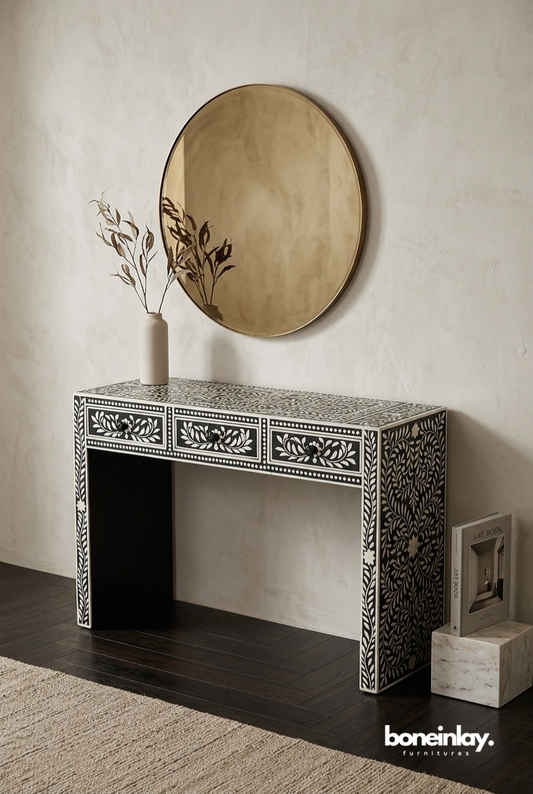 Black and white handcrafted bone inlay console table with floral vine motif, three drawers, styled with round mirror and dried stems in entryway