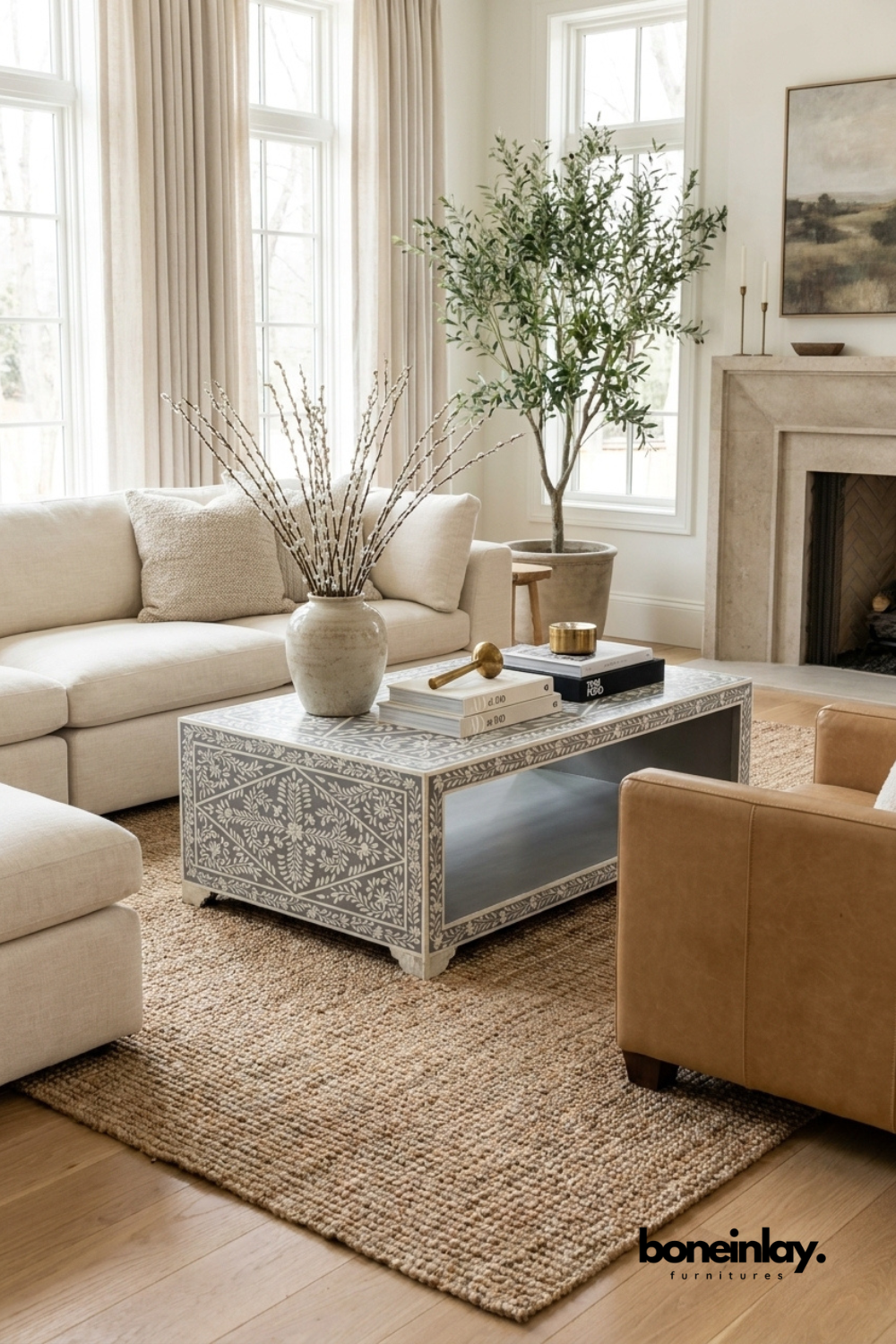 Floral bone inlay waterfall coffee table in grey and white on mango wood, styled in a bright living room with cream sofa, tan leather chair, jute rug, potted olive tree, and ceramic vase