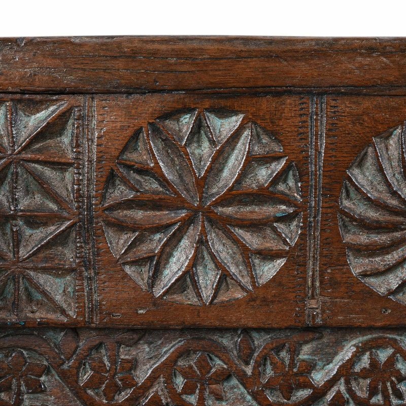Floral border hope chest in natural solid wood, edge detail view of a carved flower between geometric and spiral motifs.
