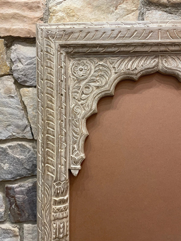 Floral carved accent mirror in rustic solid wood, corner detail view showing the scalloped arch and leaf trim.